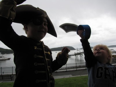 Harvey in full pirate gear and Zion with a sword, with the harbor behind them