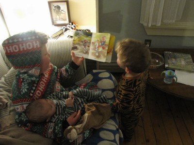 Harvey holding a baby, reading to Lijah; all in PJs