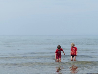 Zion and Matthew wading in the ocean in their clothes