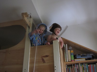 Zion and Lijah looking over the edge of the top bunk, Zion in bathrobe and Lijah in monkey hat