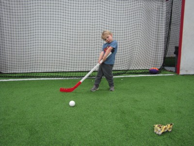 Zion posing with a hockey stick on an indoor turf field