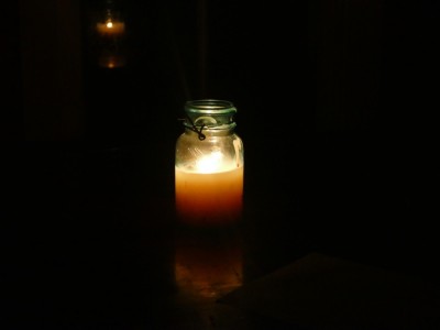 a tallow candle in a jar burning in the dark