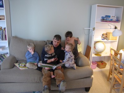 Dan on a couch reading to four little kids