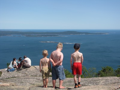 Zion, Harvey, and Nathan shirtless gazing out to sea from a mountaintop