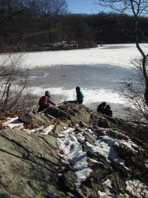 Harvey, Zion, and friends climbing on rocks above an icy pond