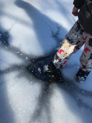 Lijah putting his foot on a clear spot on the ice