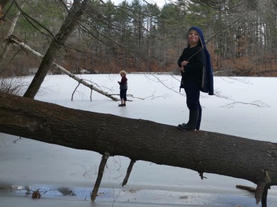 Zion walking on a fallen tree over the ice, Harvey in the background