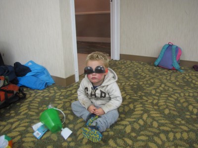 Lijah sitting on a hotel ballroom floor wearing sunglasses upsidedown