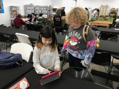 Harvey and a friend looking at an iPad at a Pokemon event