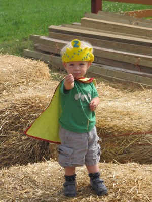 Zion standing on a hay bale wearing a cape and crown