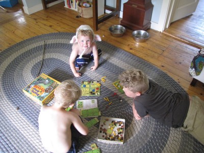 Harvey and Zion playing a board game on the rug, Lijah watching