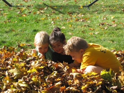 Harvey, Zion, and Kamilah playing in the leaf pile