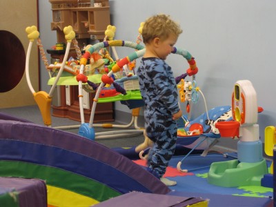 Lijah playing among many toys in a playspace