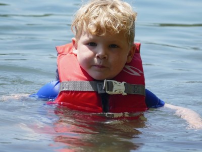 Lijah in his red life jacket almost chin deep in water
