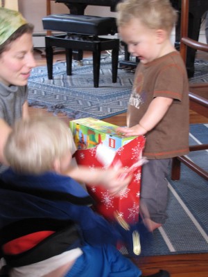 Lijah delightedly opening a present, Mama and Zion helping