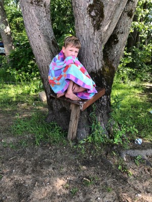 Lijah sitting on a bench in a tree wrapped up in a towel