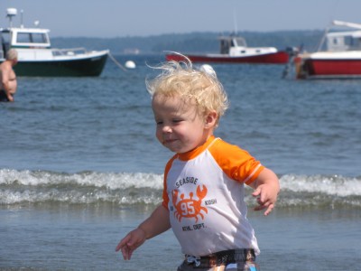 Zion running on the beach in Lincolnville, with lobsterboats in the background