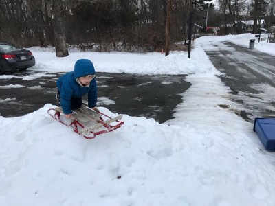 Zion on the runner sled atop a tiny mound of snow