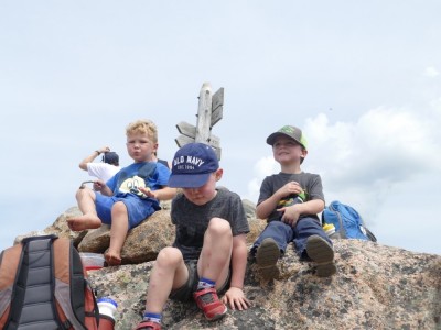 Lijah with his friends sitting on the cairn atop a mountain