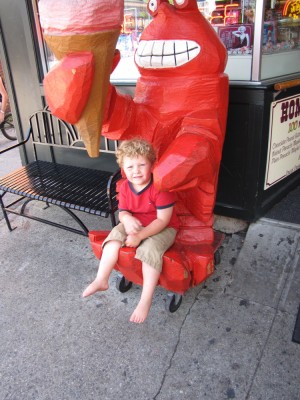Harvey sitting in the lap of a big wooden lobster holding an ice cream cone (the lobster has the cone, not Harvey)