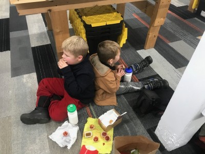 Zion and Lijah eating McDonalds on the floor of a game shop