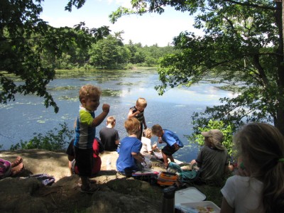 the kids eating lunch on the little cliff above the pond