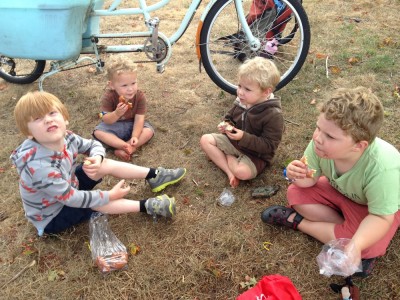 Nathan and the three boys eating donuts on the grass at the farmers market