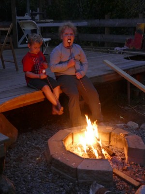 Harvey and Zion sitting by the fire with marshmallows