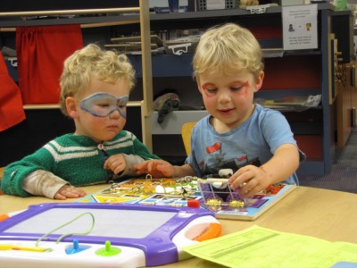 Zion and Lijah, face-painted, doing a puzzle at the library