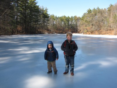 Harvey and Zion standing on the ice at the middle of the pond