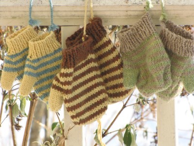 three pairs of mittens hanging on the porch rail