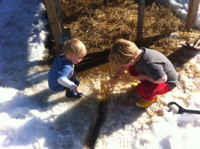 Zion and Harvey chipping ice around a muddy puddle