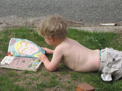 shirtless Zion lying in the front yard reading a comic