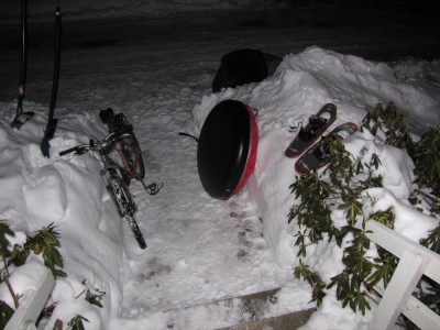 bike, sled, and snowshoes in the evening snow