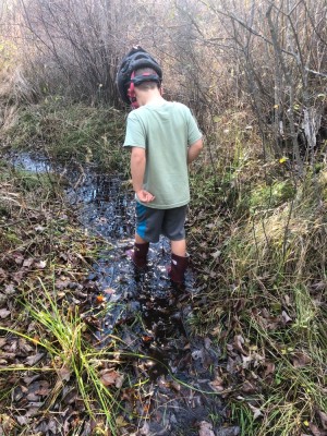 Elijah wading in a stream in his boots