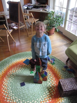 Zion smiling (sort of) with his magnatiles construction on the new rug