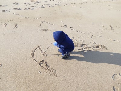 Lijah drawing in the sand with a stick