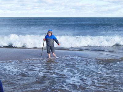 Harvey barefoot in winter coat running from the waves
