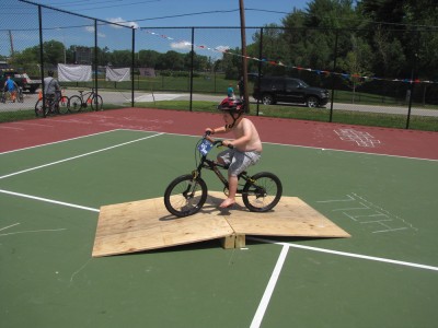 Harvey riding over a wooden ramp on the tennis court