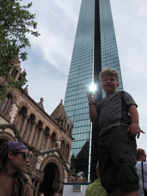 Harvey standing on a pedestal, with Trinity Church and the Prudential Tower behind him