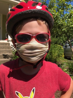 Lijah in his mask and red shirt, bike helmet, and sunglasses
