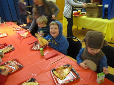 the three boys sitting at the birthday table, with pizza