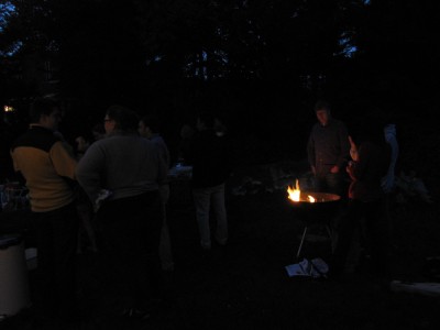 in the dark, guests gather around the fire in the kettle grill