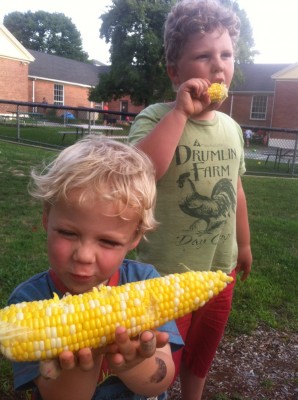 Zion and Harvey eating corn on the cob by the playground