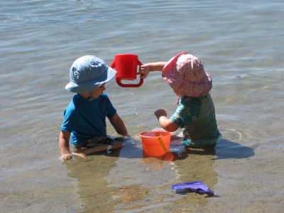 two smallish children playing around the fish bucket
