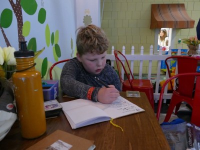 Harvey writing in his notebook homework at the playspace