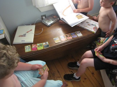 boys and friends playing with pokemon cards