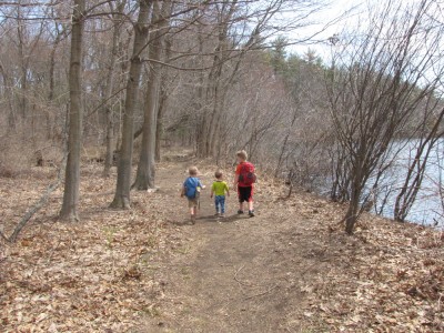 three boys walking together around the pond