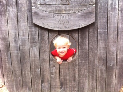 Zion smiling through a porthole in a playground ark