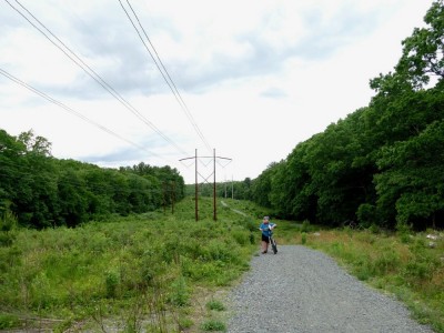 Harvey walking his bike up a steep hill on a path beneath high-tension lines
